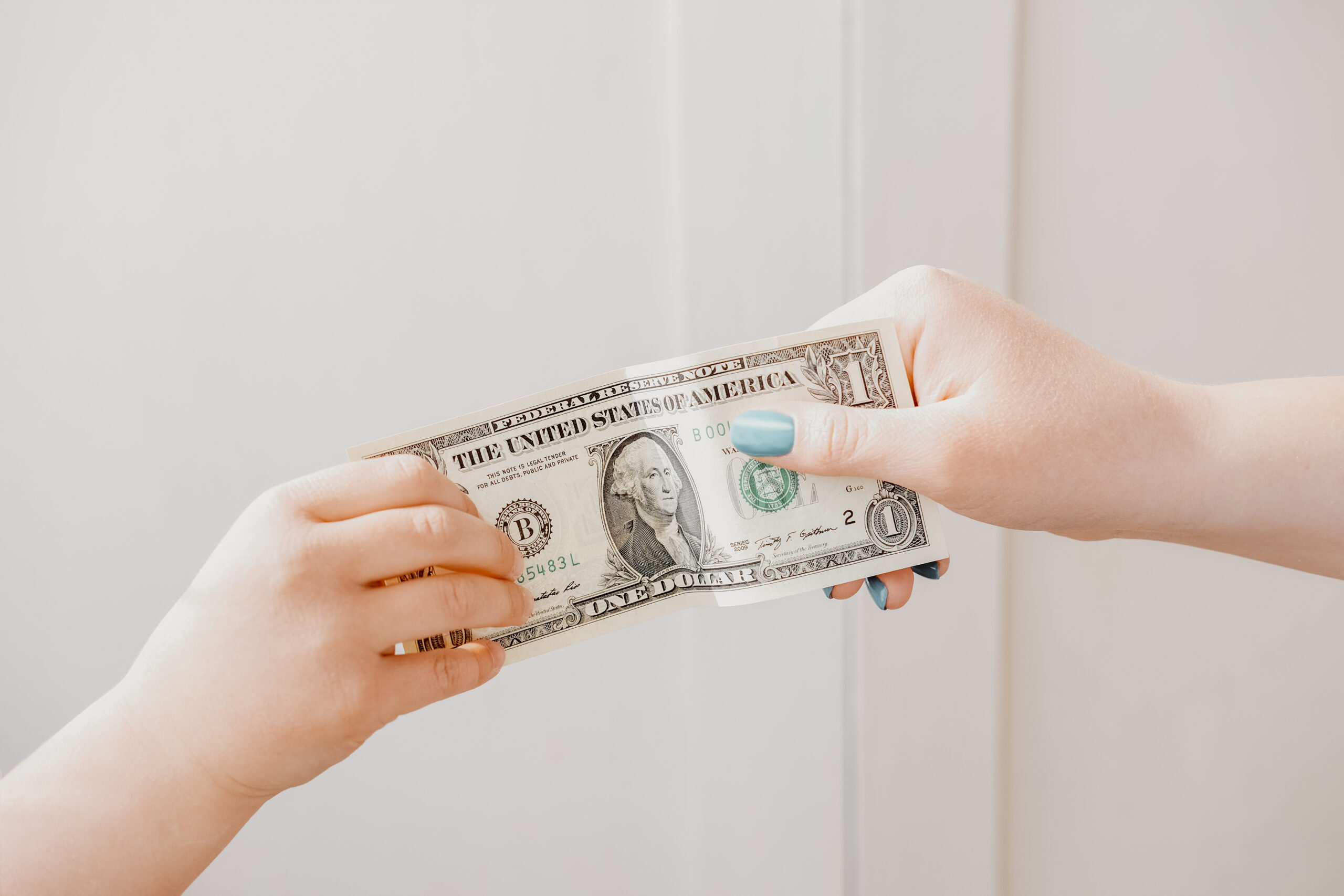 Pocket money concept. woman's hand giving dollar note to a child.