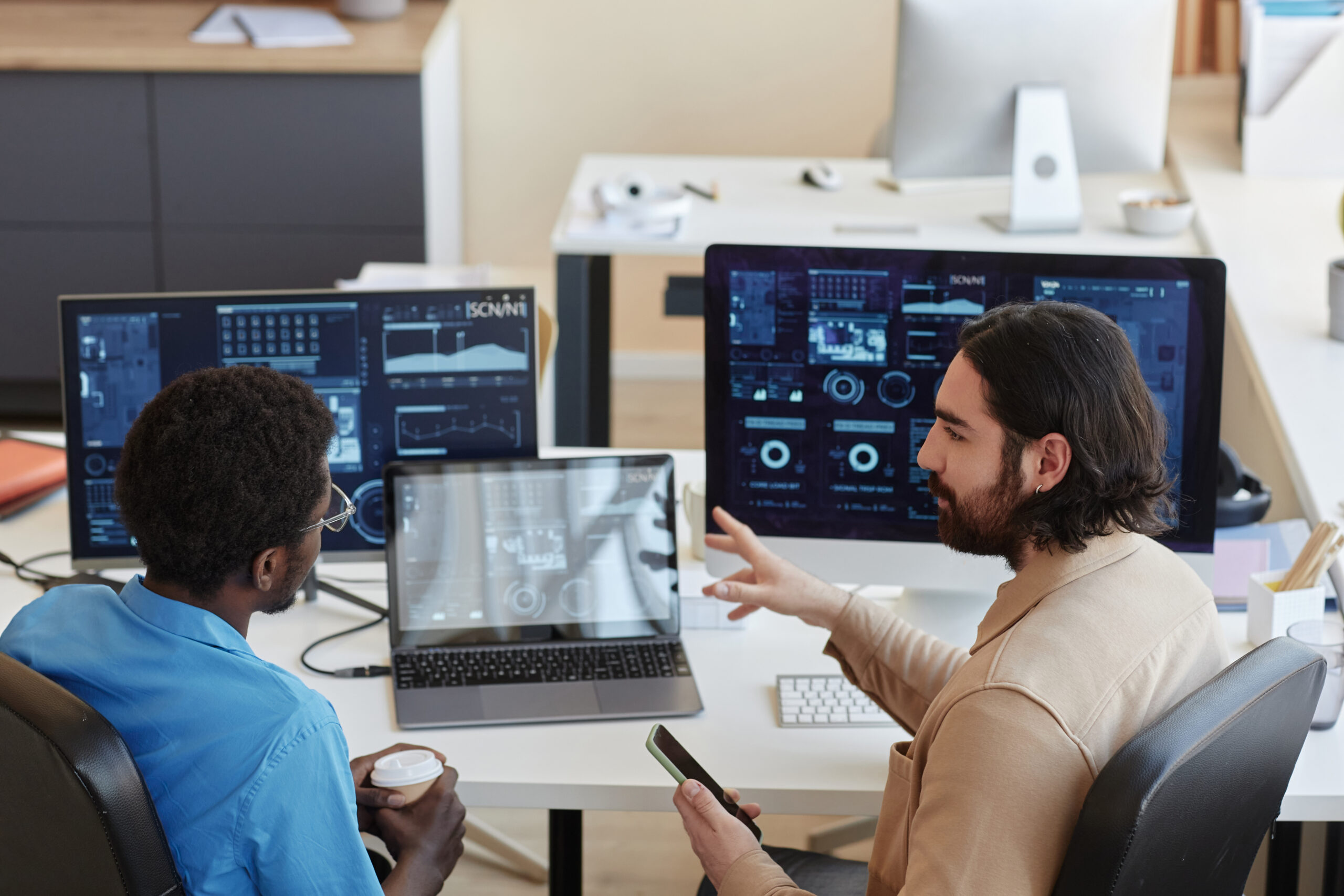Young confident IT engineer explaining graphic data to his colleague
